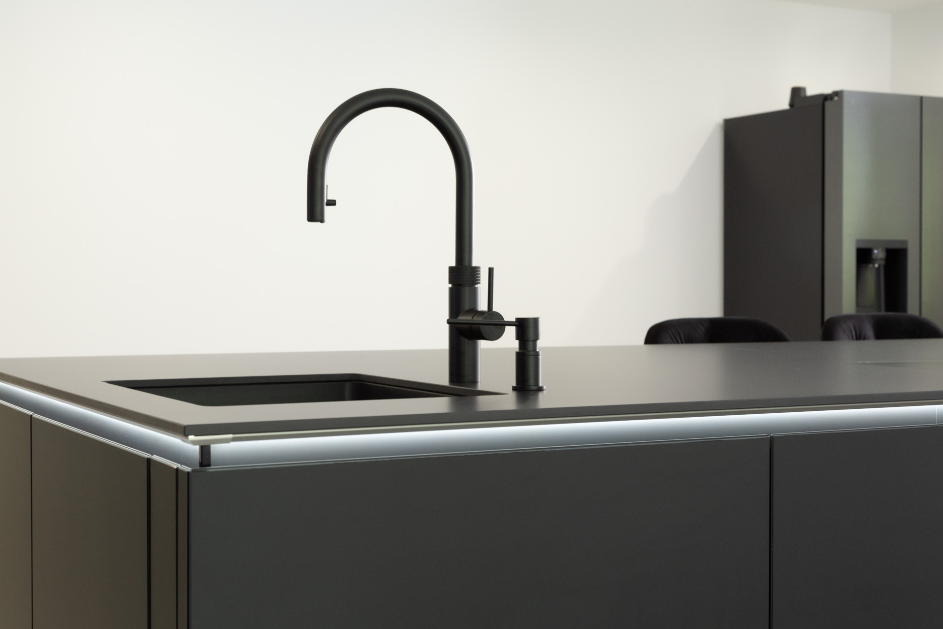 Schwarze Küche mit viel Schrankfläche - Spüle mit Armatur als Teilansicht
